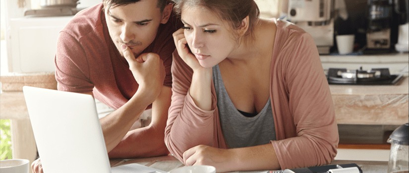 Banner image of a young couple reviewing financial information on a laptop screen