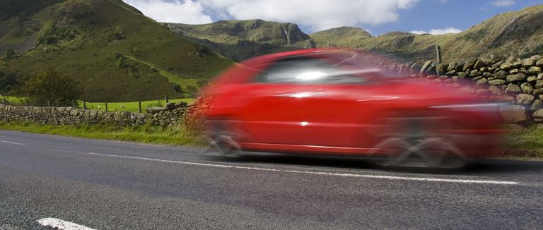 Banner image of red car travelling on country road