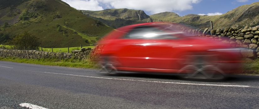Banner image of red car travelling on country road